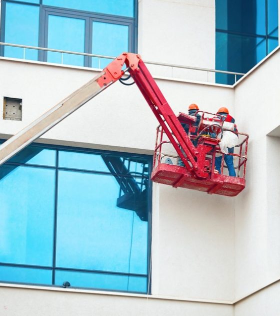 Two men on a lift painting a commercial building