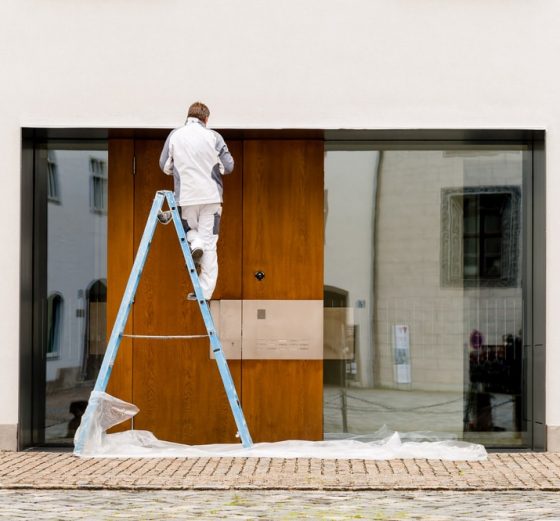 Man On A Ladder Painting A Commercial Building